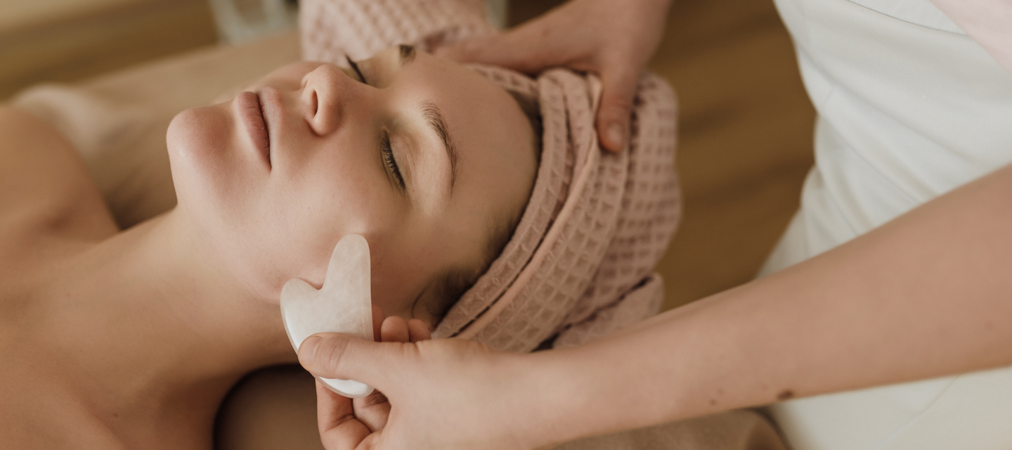 Client relaxing during facial massage with gua sha stone